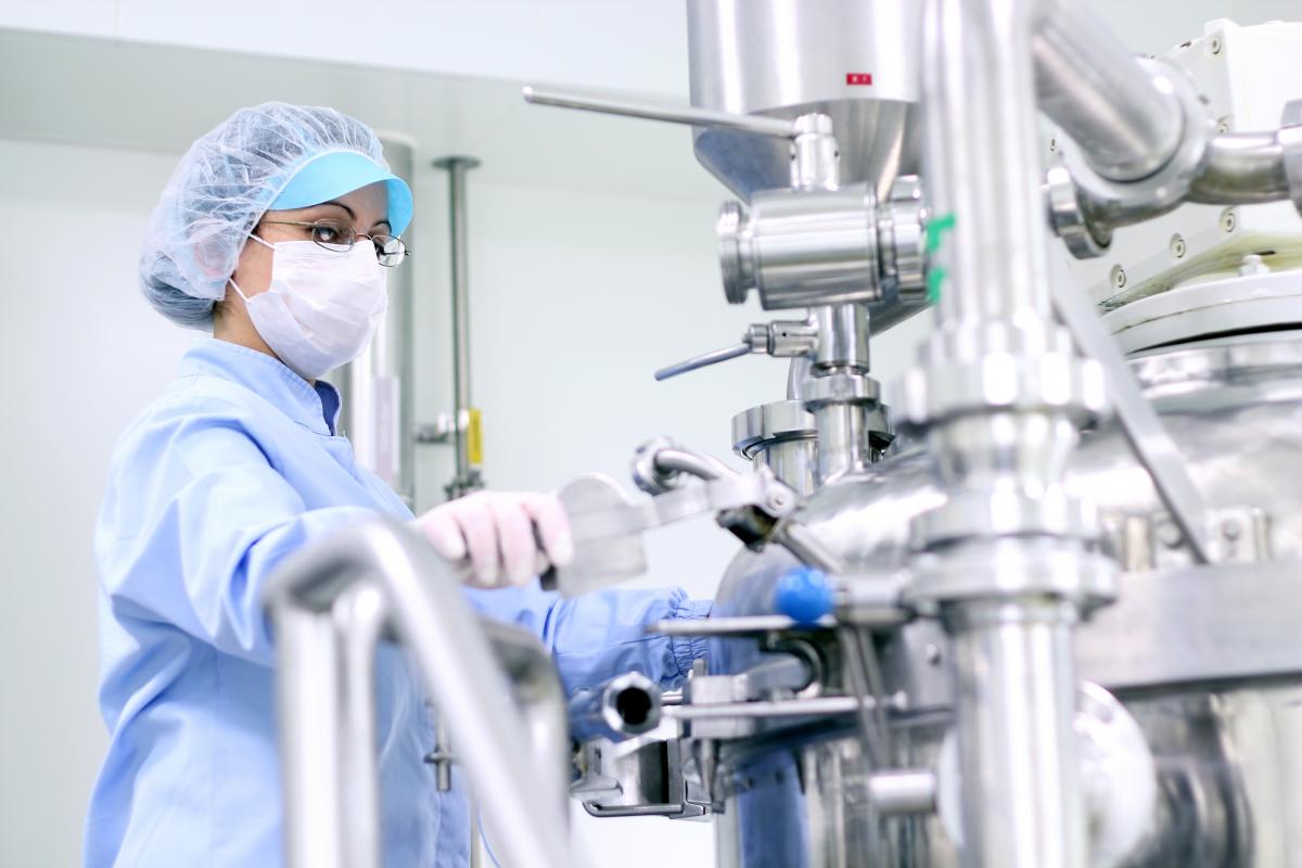 Woman wearing PPE operating a large machine